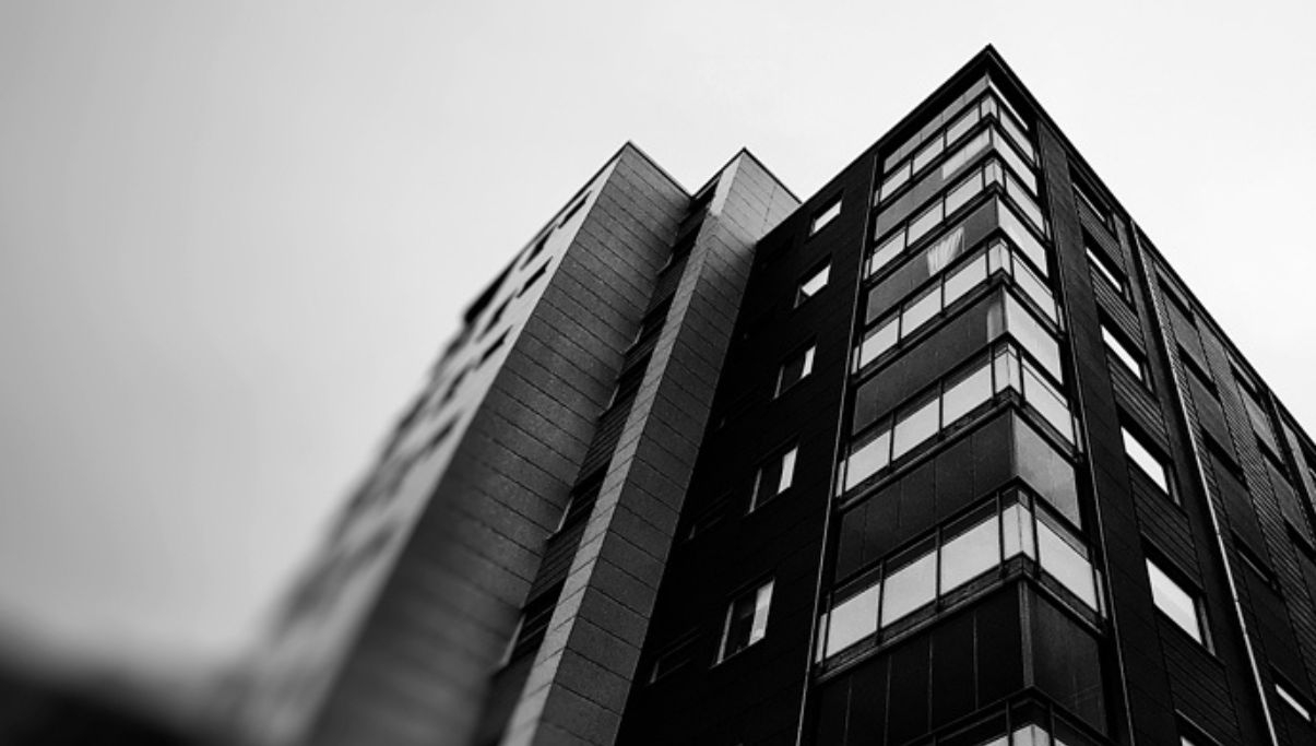 Svartvitt foto underifrån på ett modernt flerbostadshus med många fönster och balkonger, en typisk fastighet där Ultraputs utför fönsterputs åt bostadsrättsföreningar.